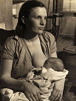 A young woman from a poor migrant farming family nurses her baby in the family's shack at a labor camp